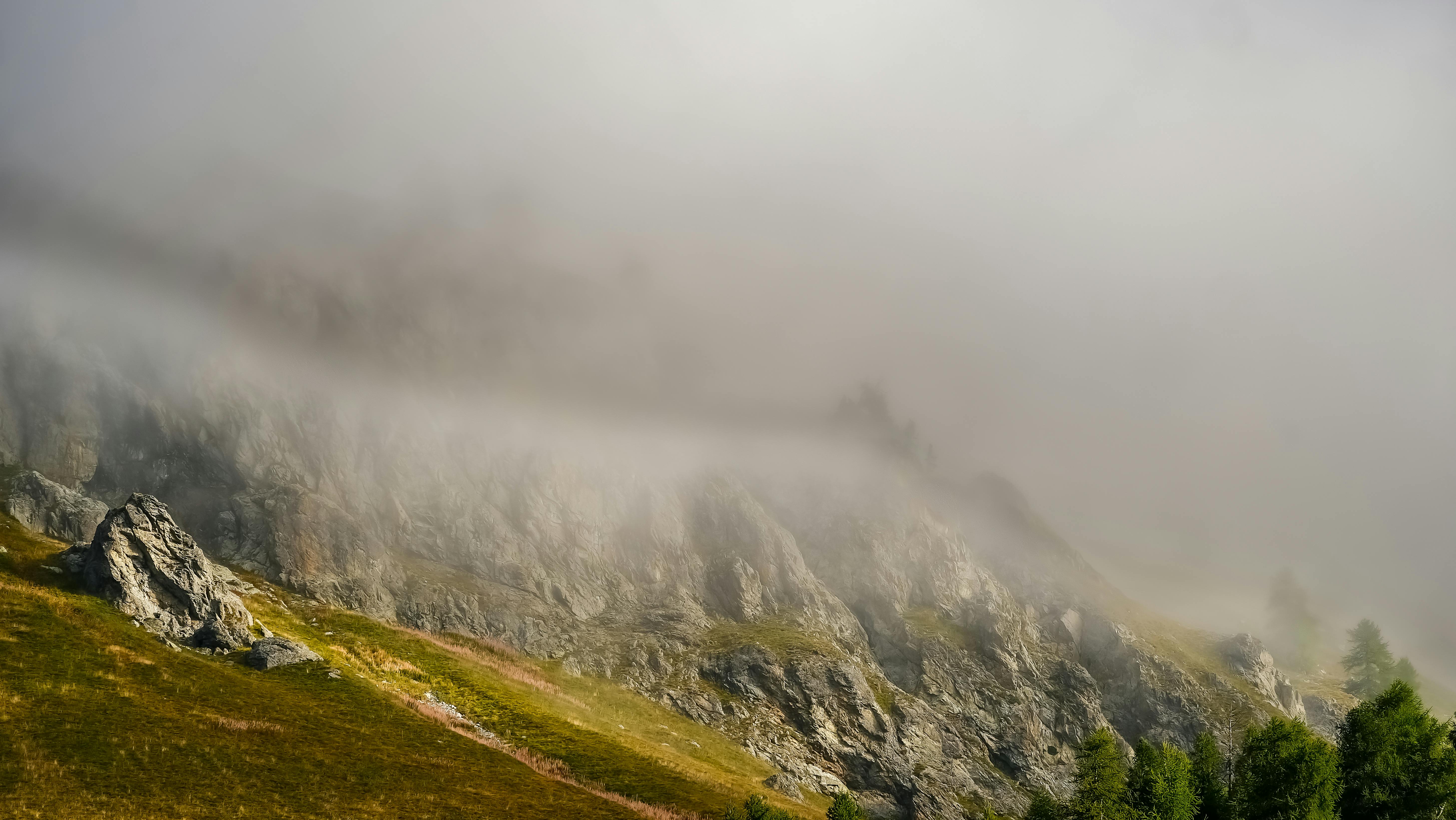 Serene misty mountain scene with lush greenery and rocky terrain.