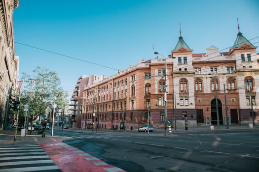 A vibrant street scene of a European city featuring historic architecture and a clear blue sky.