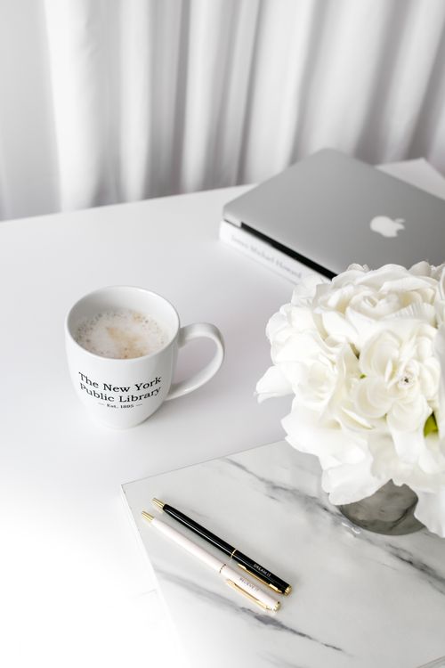 Free A clean desktop setup featuring a laptop, coffee mug, and white flowers. Stock Photo