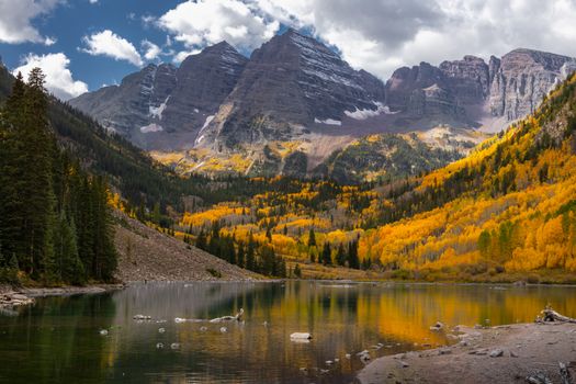 Stunning autumn landscape of Maroon Bells with golden foliage and a serene lake reflection.