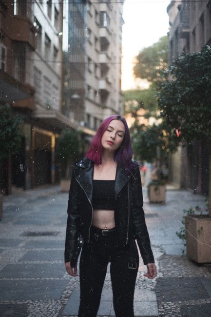Portrait of a stylish woman in black attire posing in a city street with a confident expression.