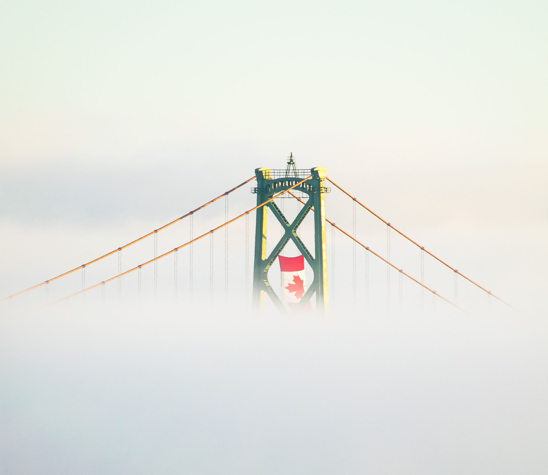 The Canadian Flag Hangs Above A Suspension Bridge