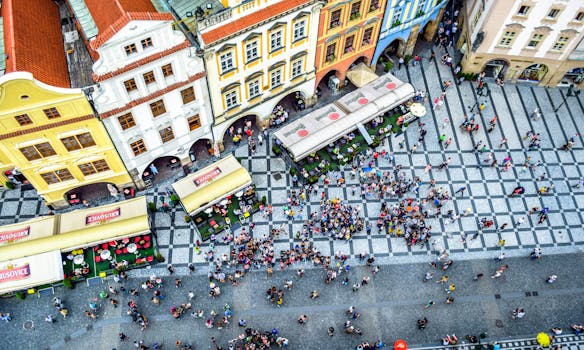 Aerial view of a bustling crowd in Prague's historic square, surrounded by colorful buildings.