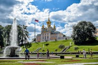 彼得霍夫宫花园里，游客们在阳光明媚的日子里，与喷泉一同享受着充满活力的夏季场景