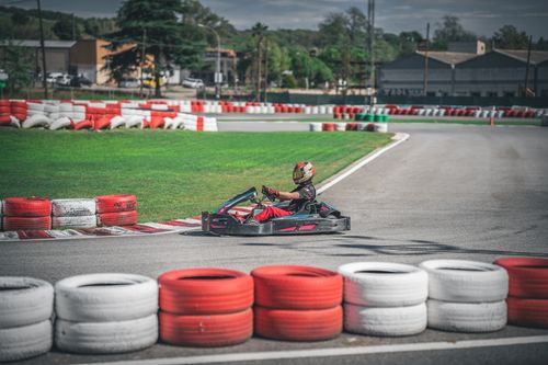 Free Driver in go-kart racing on outdoor track surrounded by colorful tires. Stock Photo