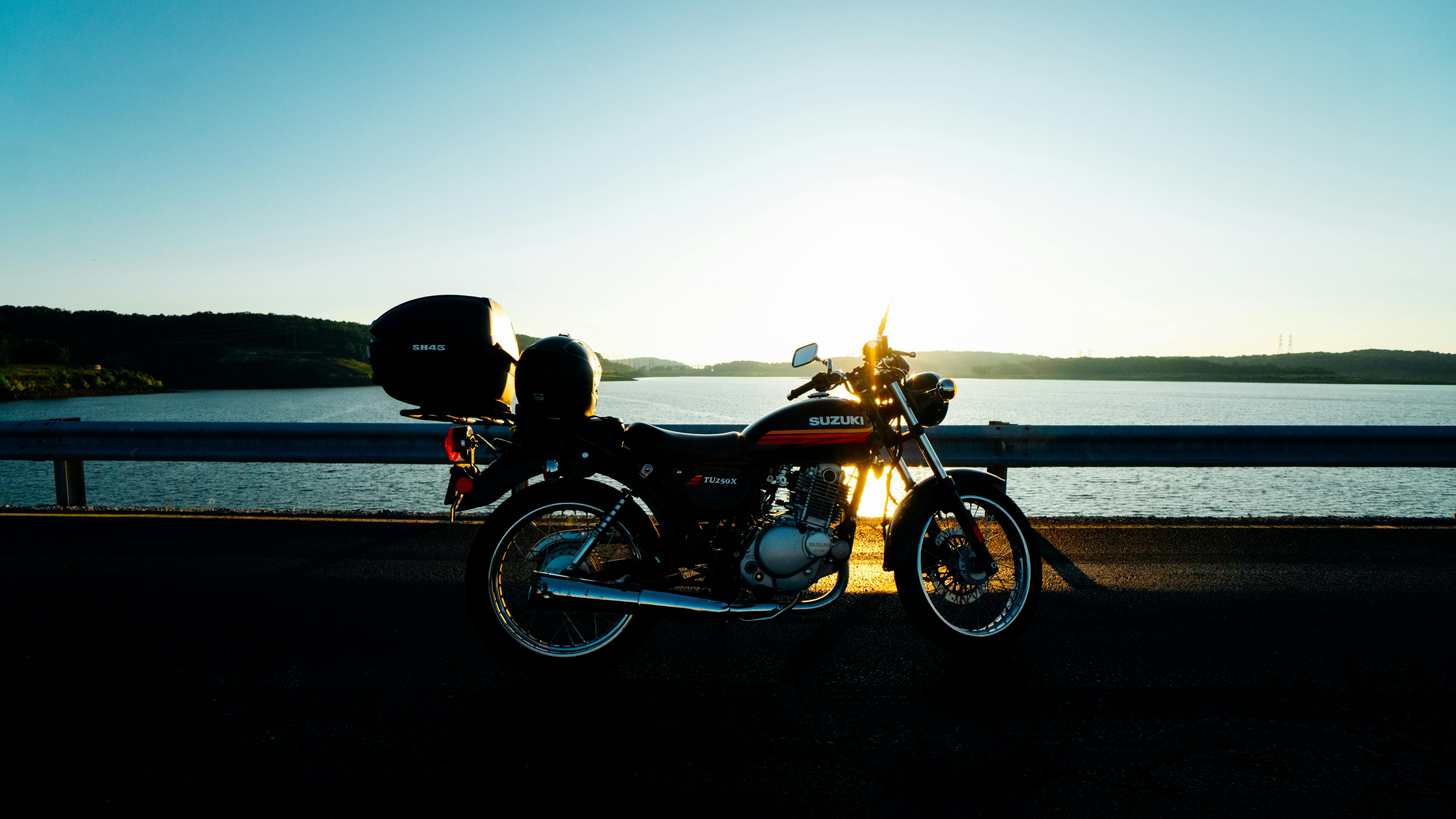 宁静的湖边，一辆经典的铃木摩托车停在日落时分