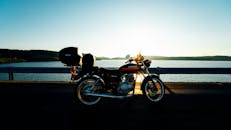 宁静的湖边，一辆经典的铃木摩托车停在日落时分