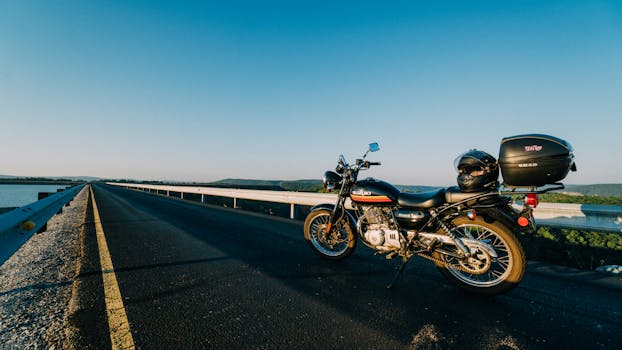 日落时分，一条开放的高速公路旁停着一辆摩托车，可以欣赏到风景优美的水景