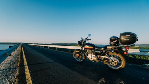 Free Motorcycle parked on an open highway with a scenic water view during sunset. Stock Photo