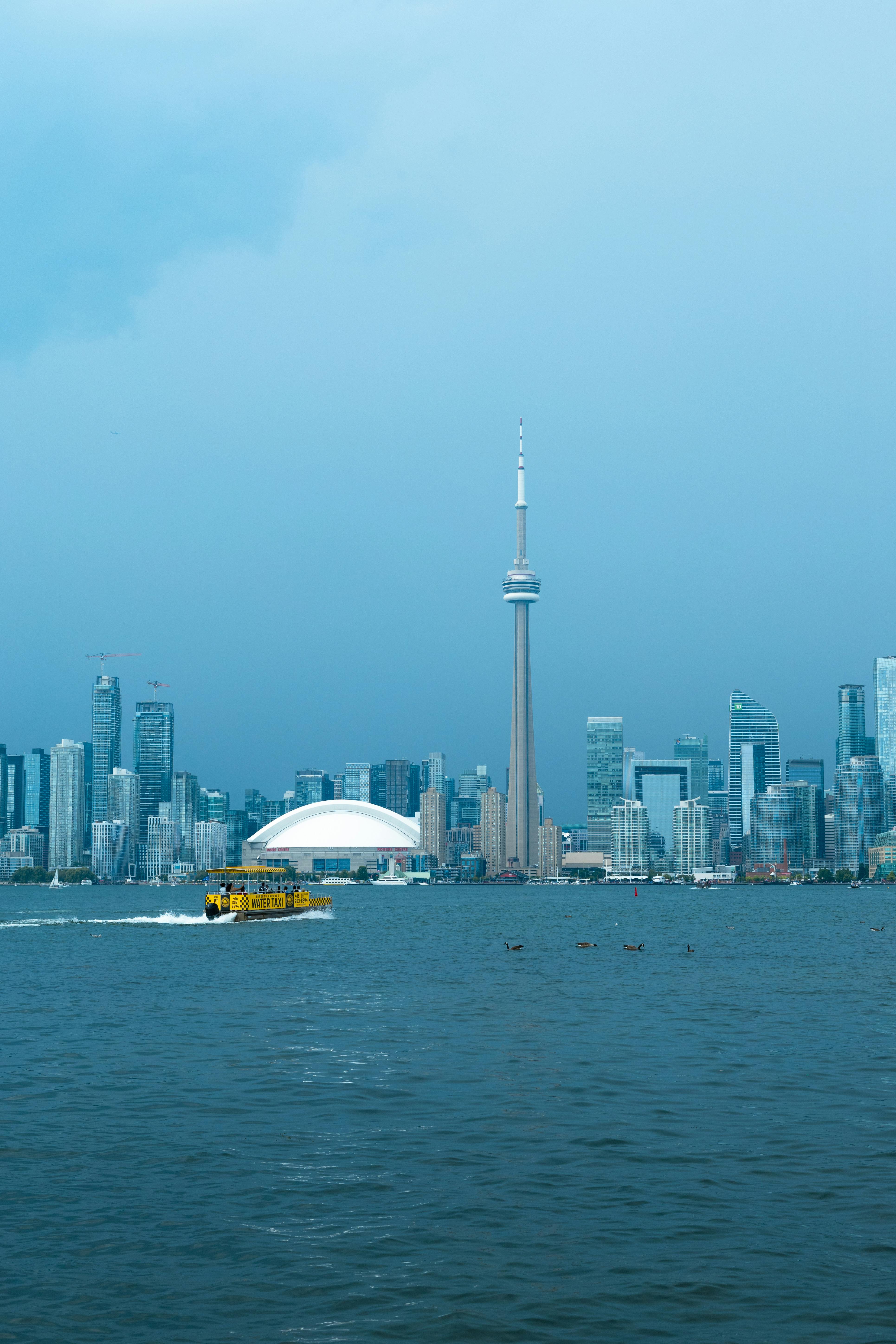 Scenic view of Toronto skyline featuring the CN Tower, Rogers Centre, and Lake Ontario with a water taxi.