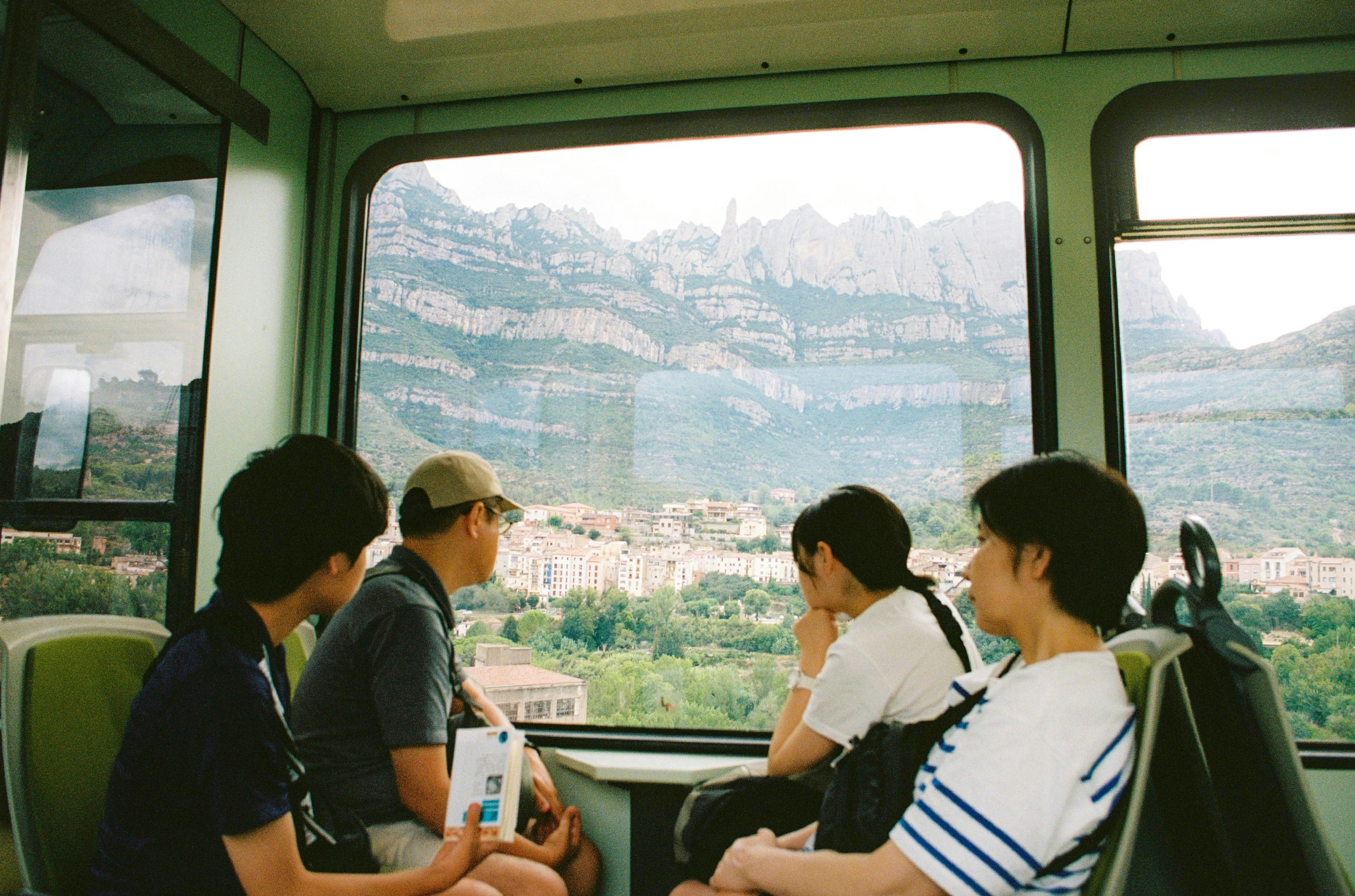Passengers admire the breathtaking view of Montserrat, captured through a train window.
