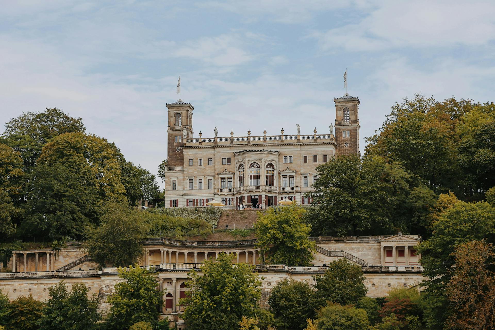 Beautiful historic castle amidst lush trees under a bright sky, perfect for travel and history themes.