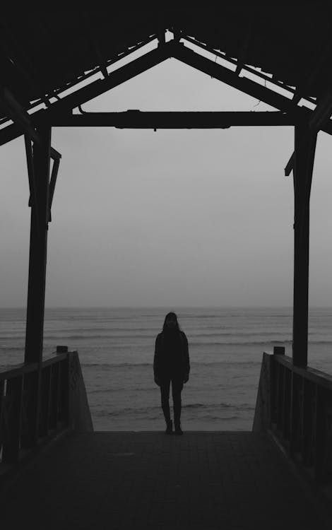 Free A Woman Standing On A Boardwalk Stock Photo