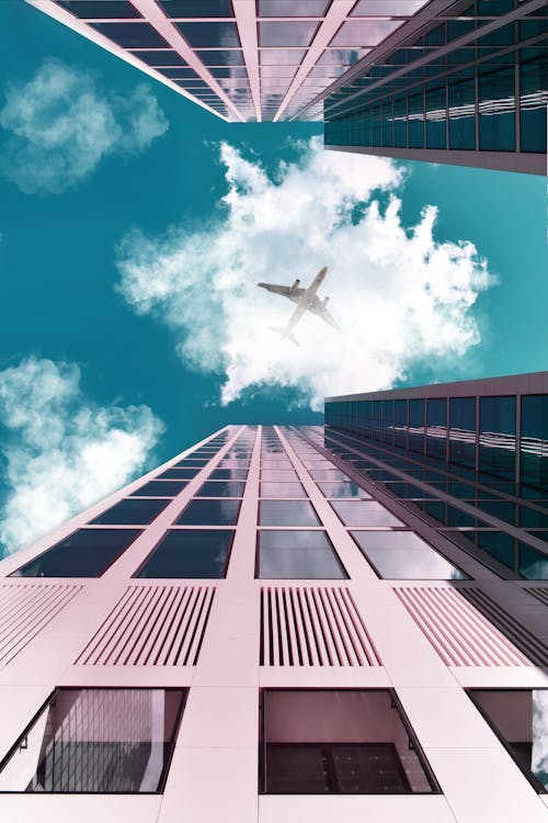 Free An Airplane Flying Over The Buildings Stock Photo