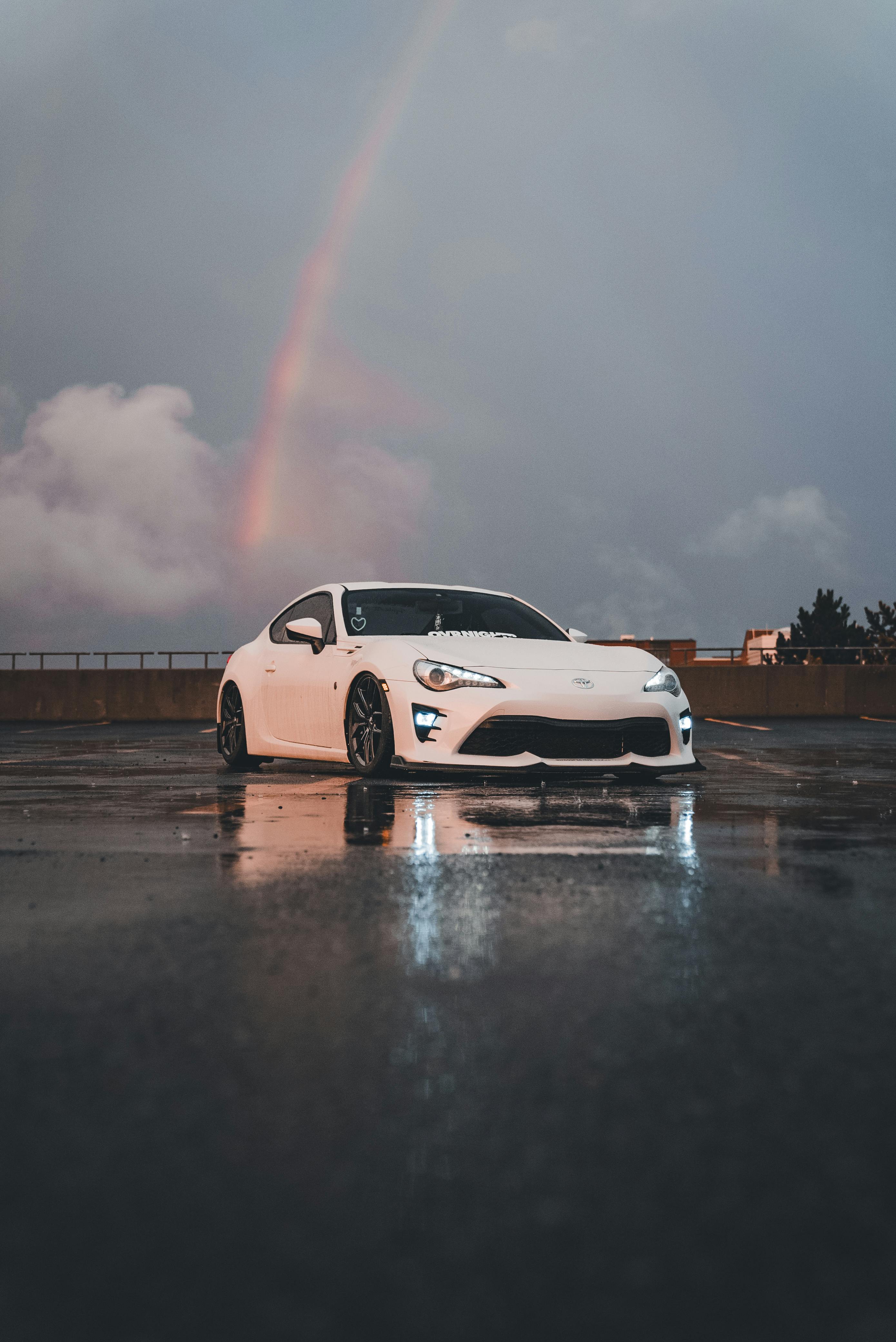 white sports car under a rainbow on wet road