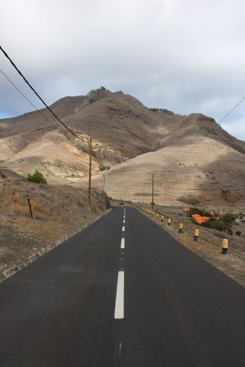 Free Long road leading through a barren mountain landscape under a cloudy sky. Stock Photo