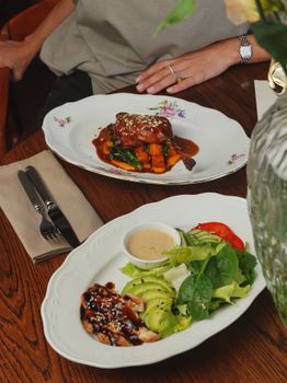 Gourmet meals elegantly presented on a wooden dining table, showcasing vibrant ingredients.