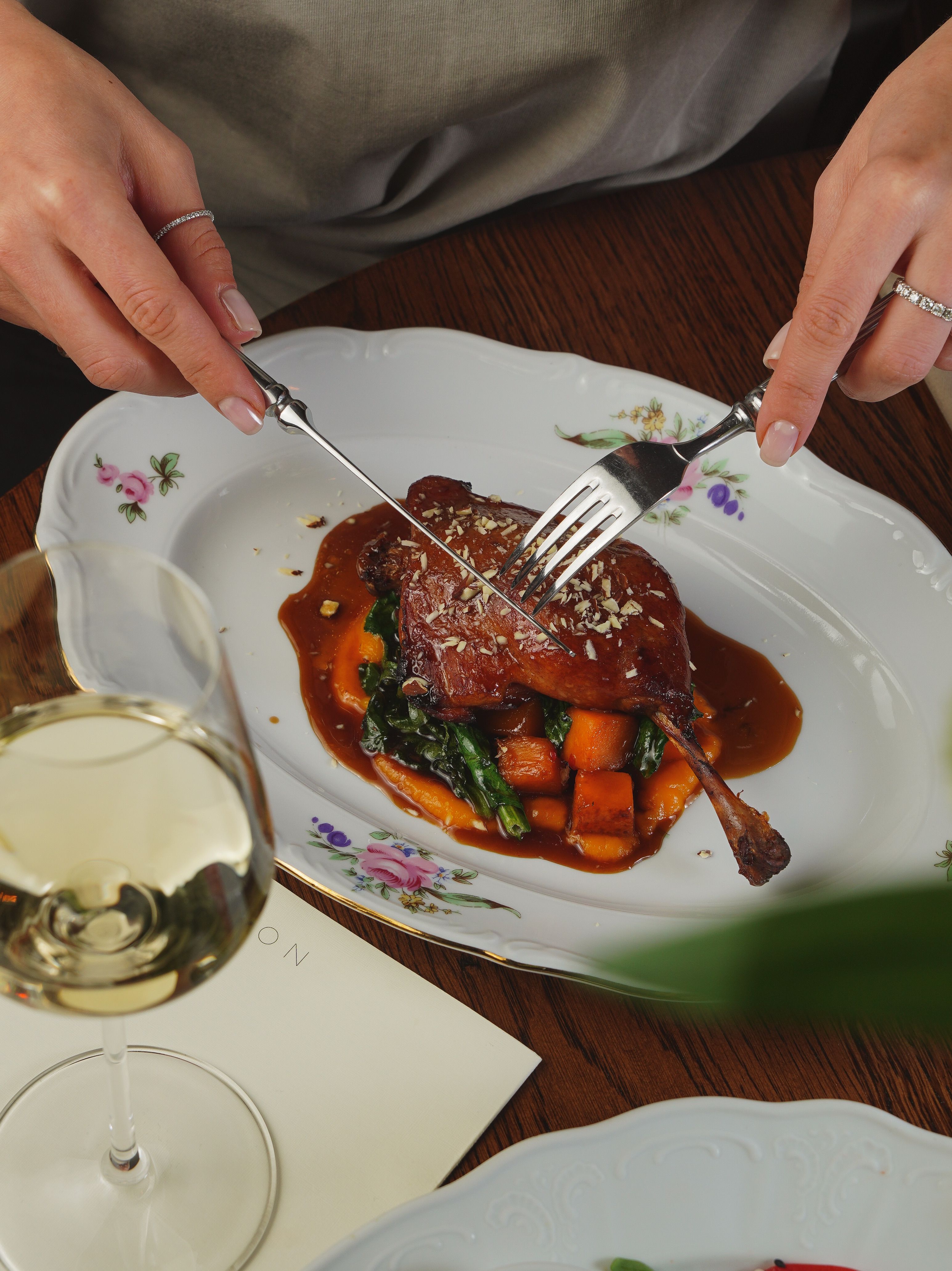 Gourmet duck meal elegantly served with wine in a sophisticated dining setting.