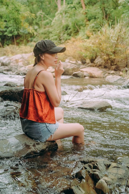 Free A Woman Sitting On A River Rock Stock Photo