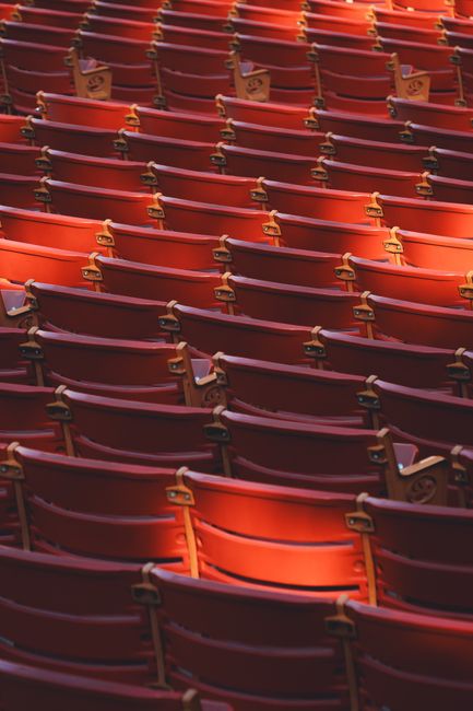 Rows of empty red theater seats illuminated by warm lighting.