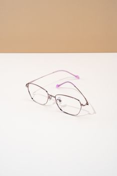 Elegant minimalist eyeglasses resting on a white table with a beige background.