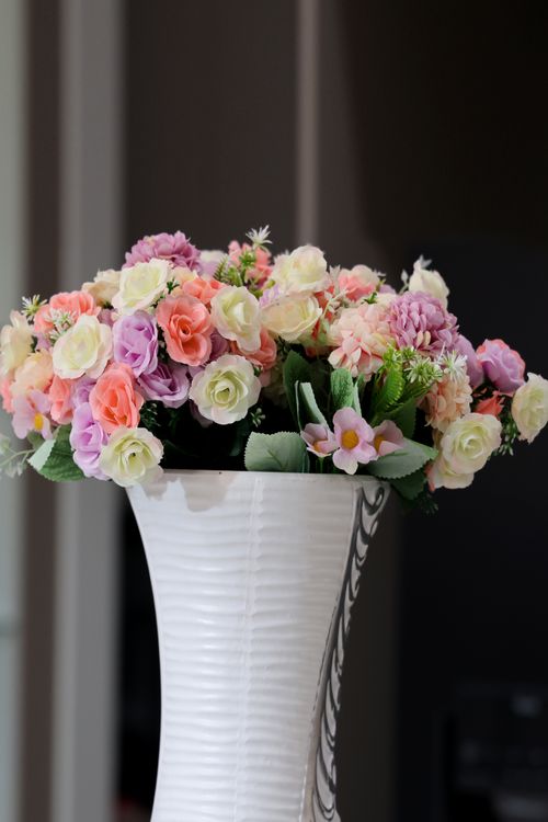 Free A vibrant bouquet of artificial flowers in pastel colors housed in an elegant white vase indoors. Stock Photo