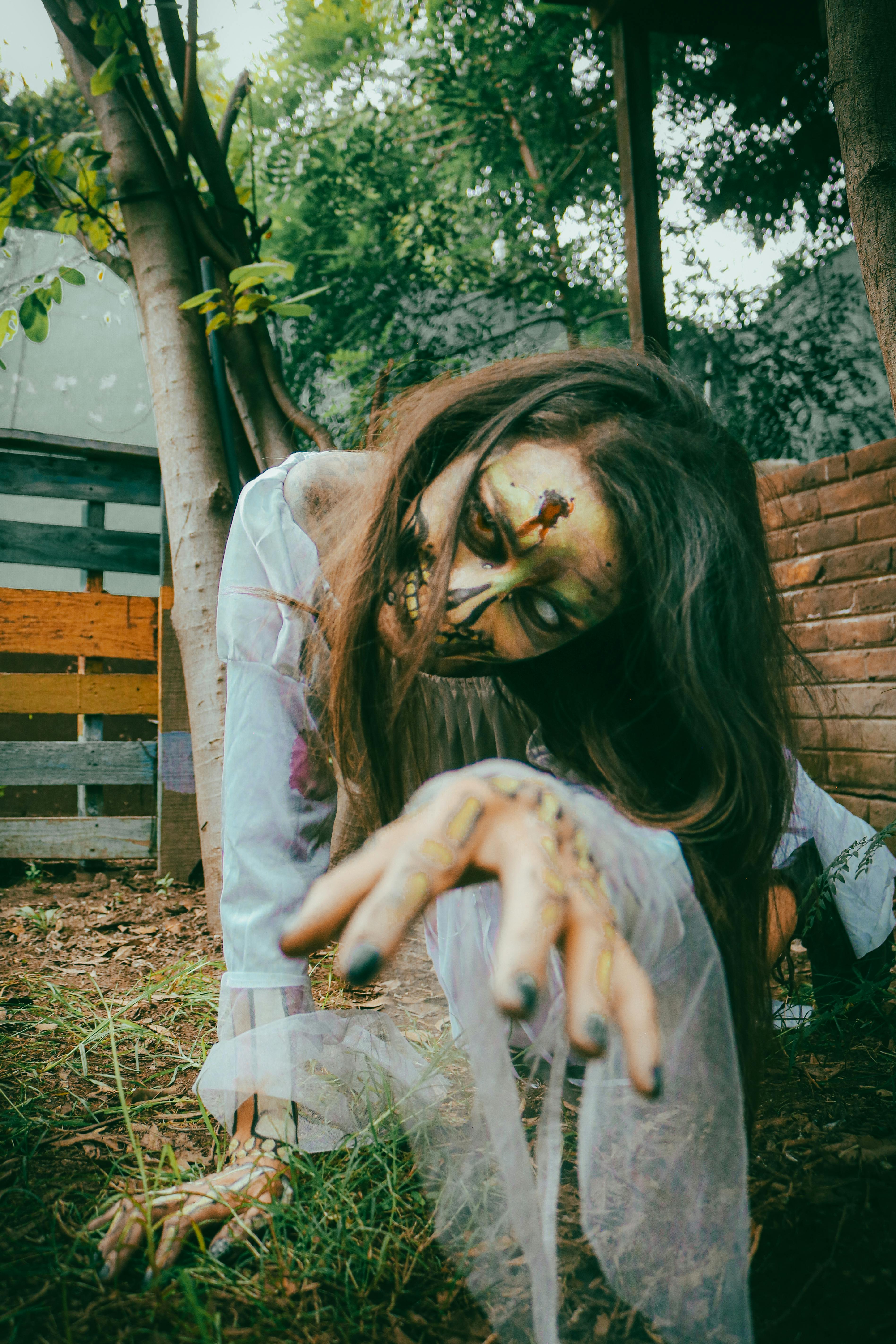 A haunting image of a zombie woman reaching out in an eerie outdoor scene.