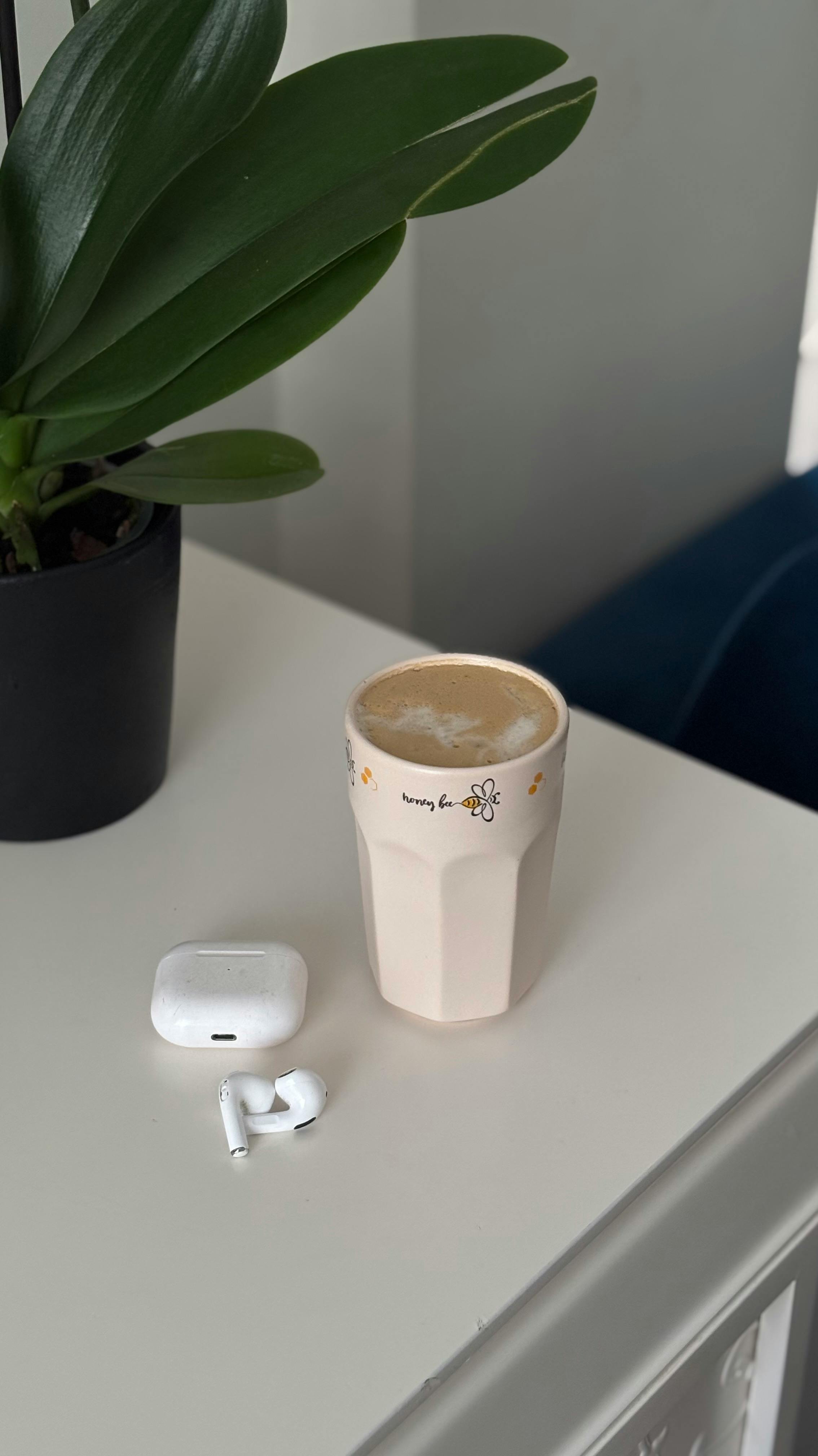 cozy coffee moment with earbuds and potted plant