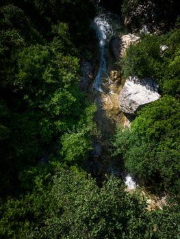 A stunning aerial view of a waterfall cascading through lush green forest in a natural setting.