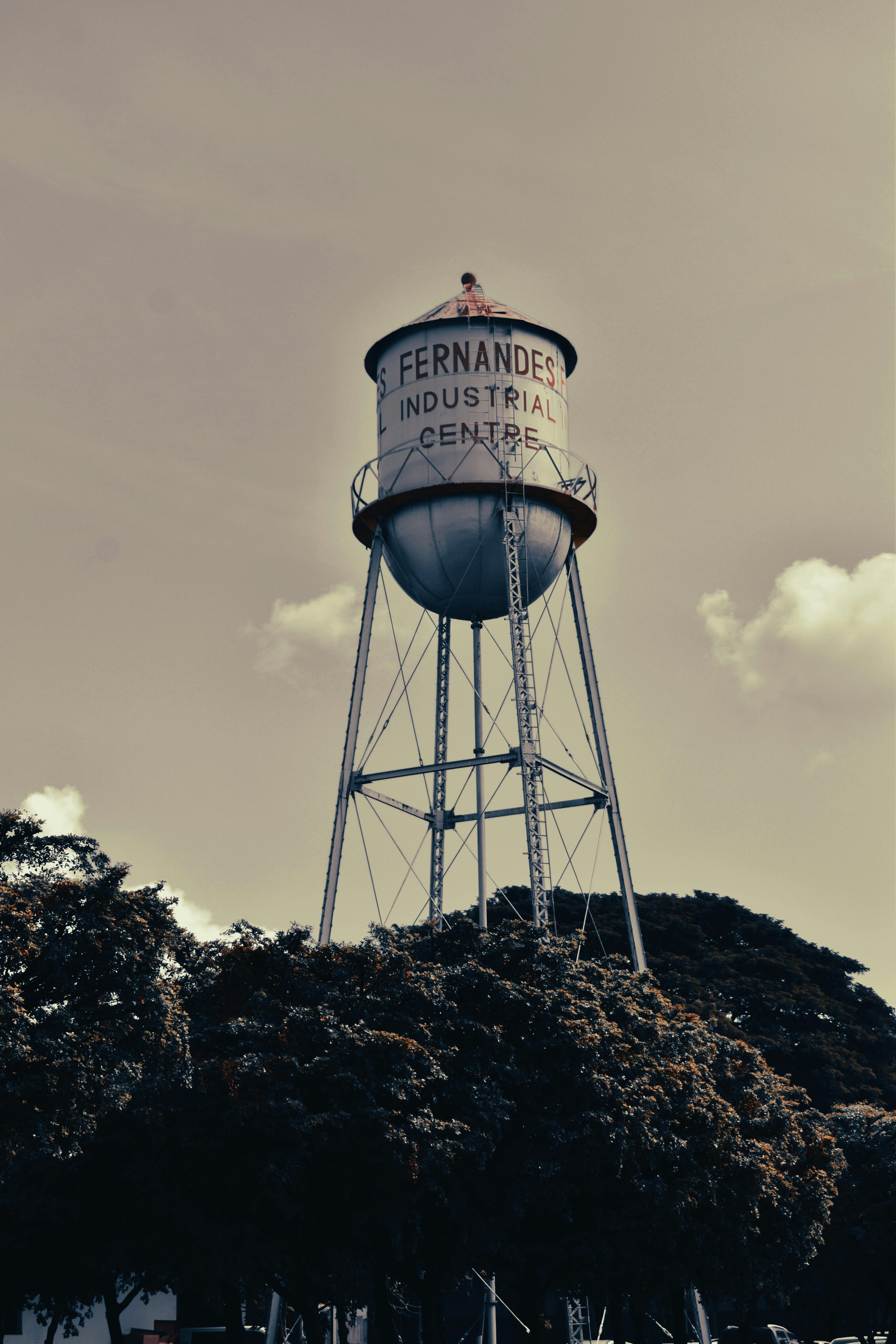 A sepia-toned image of a vintage water tower labeled 'Fernandes Industrial Centre' against a clear sky.