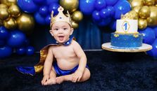 Cute baby boy dressed as a prince celebrating his first birthday with a royal theme.