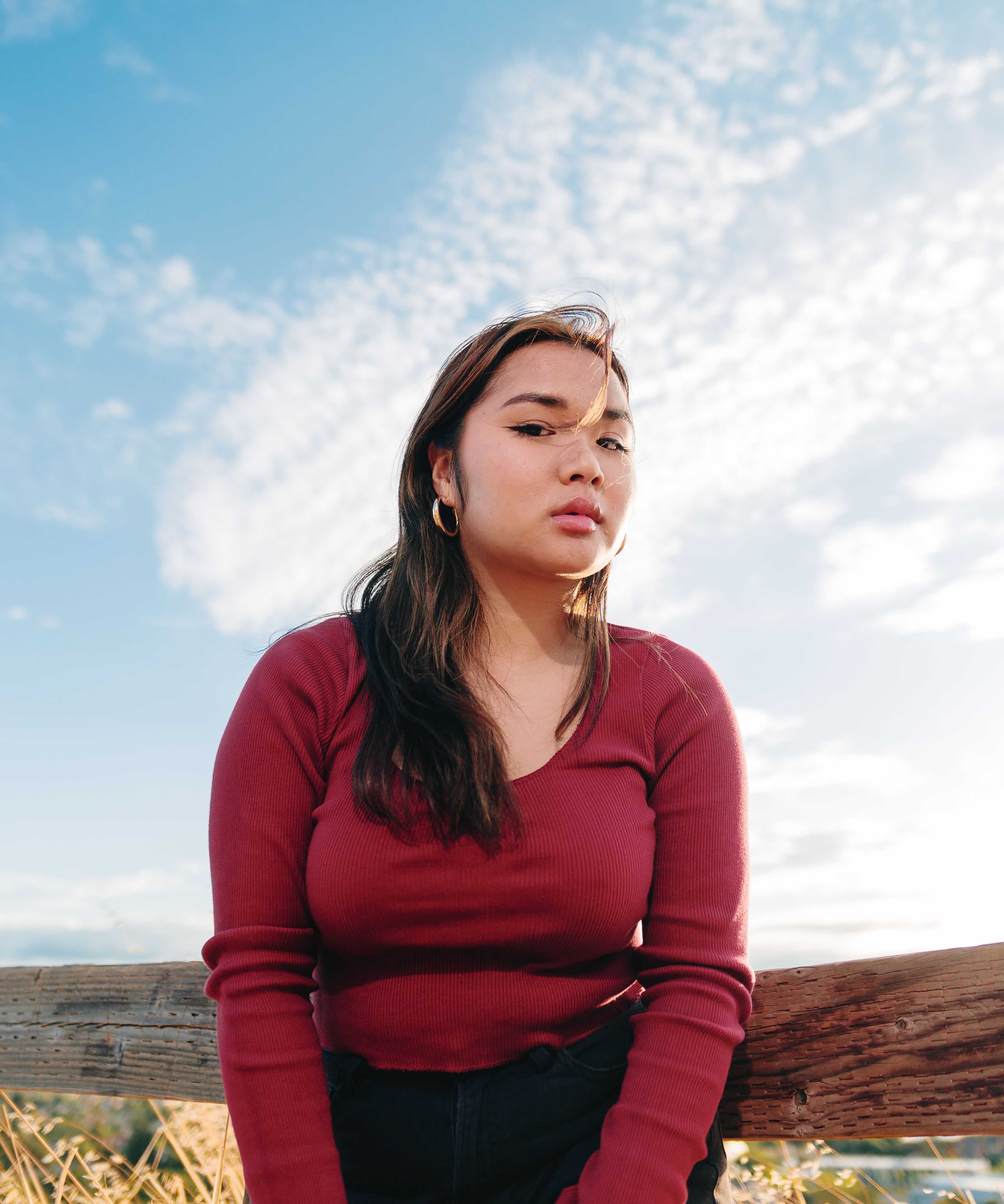 Young Woman Posing Outdoors Under Blue Sky · Free Stock Photo