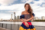 穿着鲜艳连衣裙的时尚女性在河滨城市景观中摆姿势