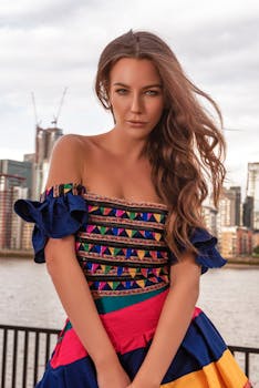 一位年轻女子身着彩色礼服，自信地站在城市背景前