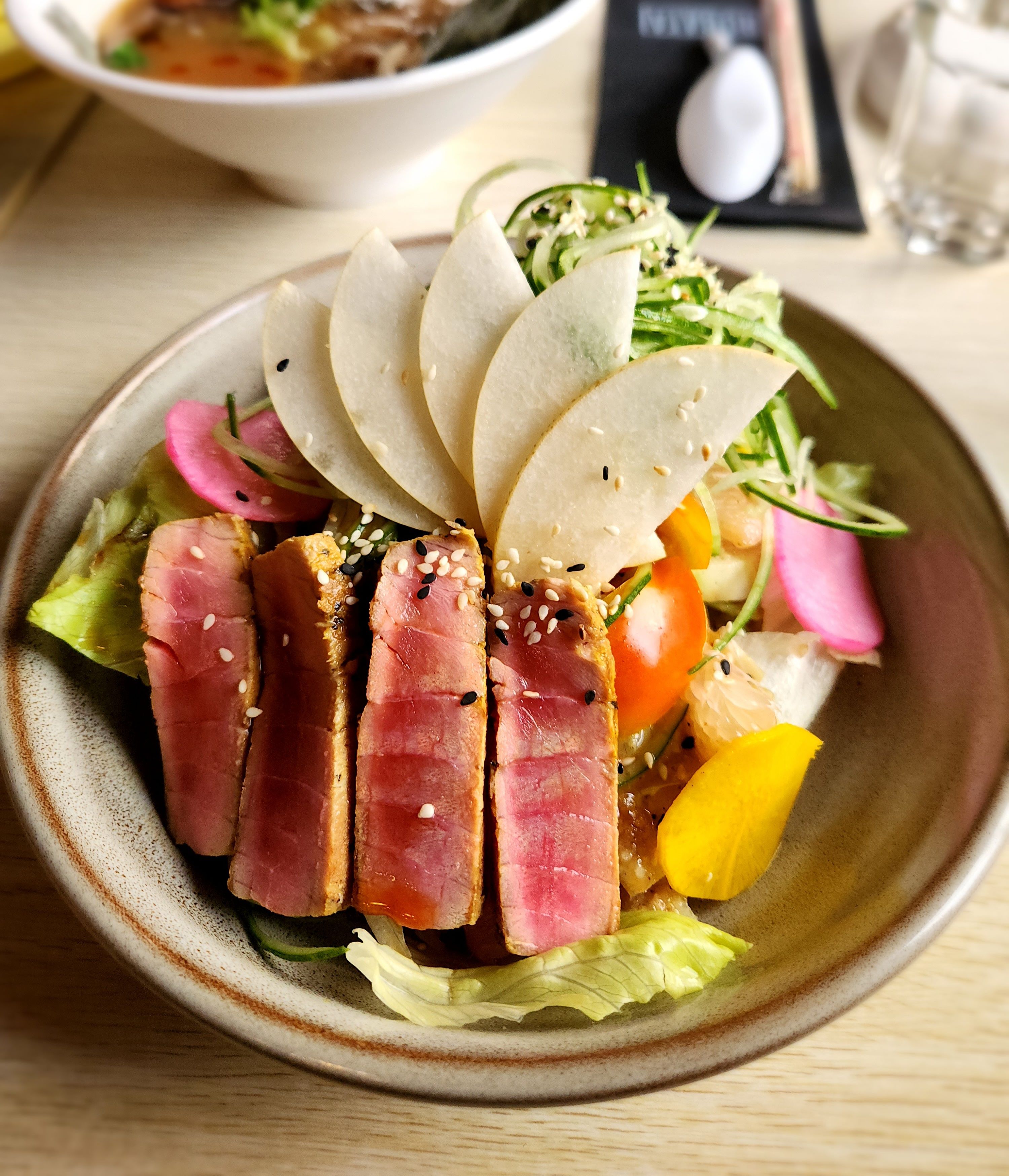 A bowl of fresh ahi tuna salad topped with sesame seeds and vegetables.