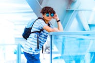Man Wearing Blue and White Stripe Shirt Leaning on Stainless Steel Handrail
