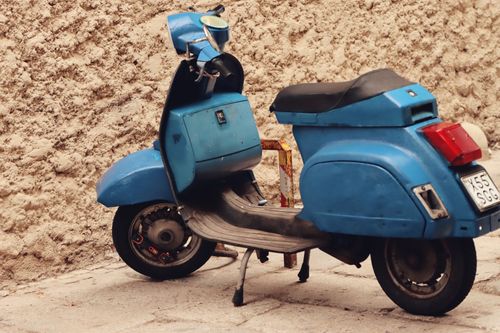 Free Vintage blue scooter parked by a stone wall in Cagliari, Sardinia. Stock Photo