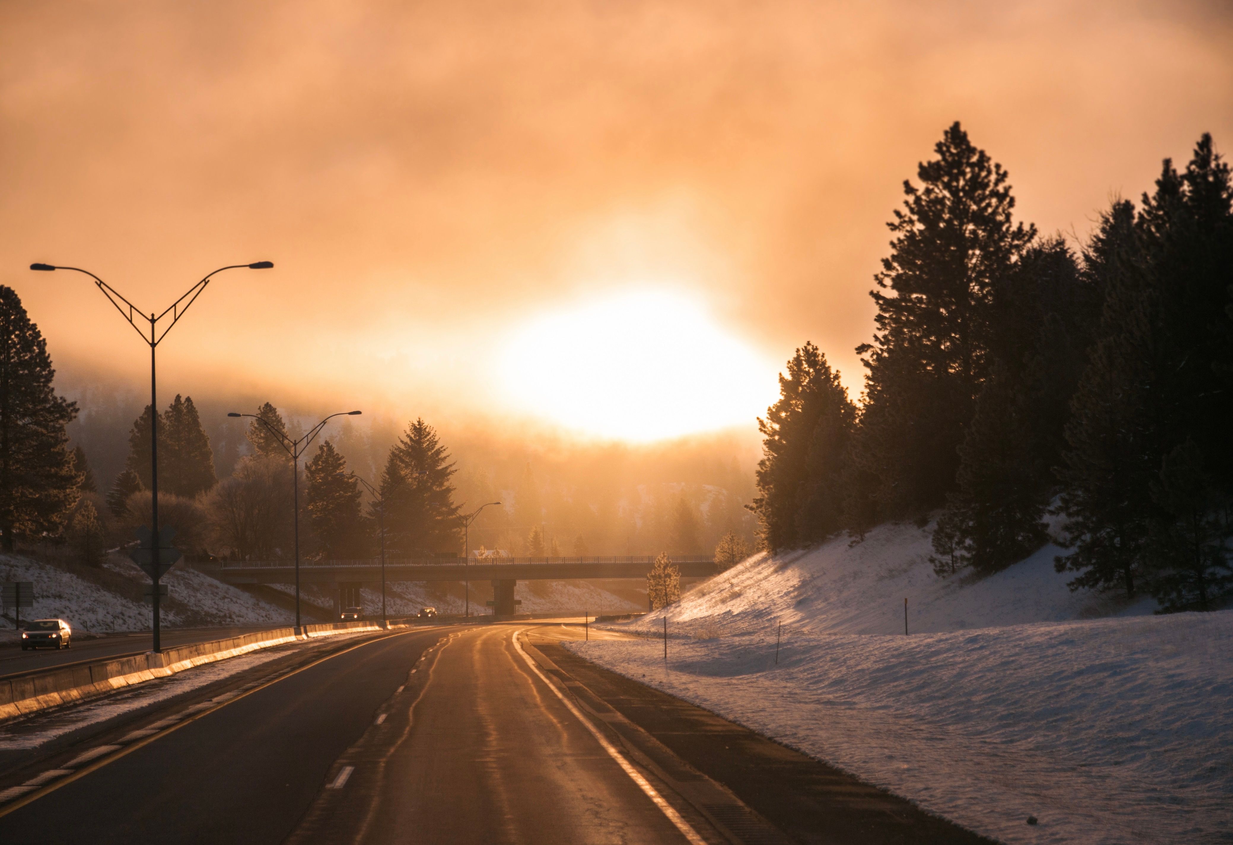 A quiet winter road at sunrise with warm light on the horizon