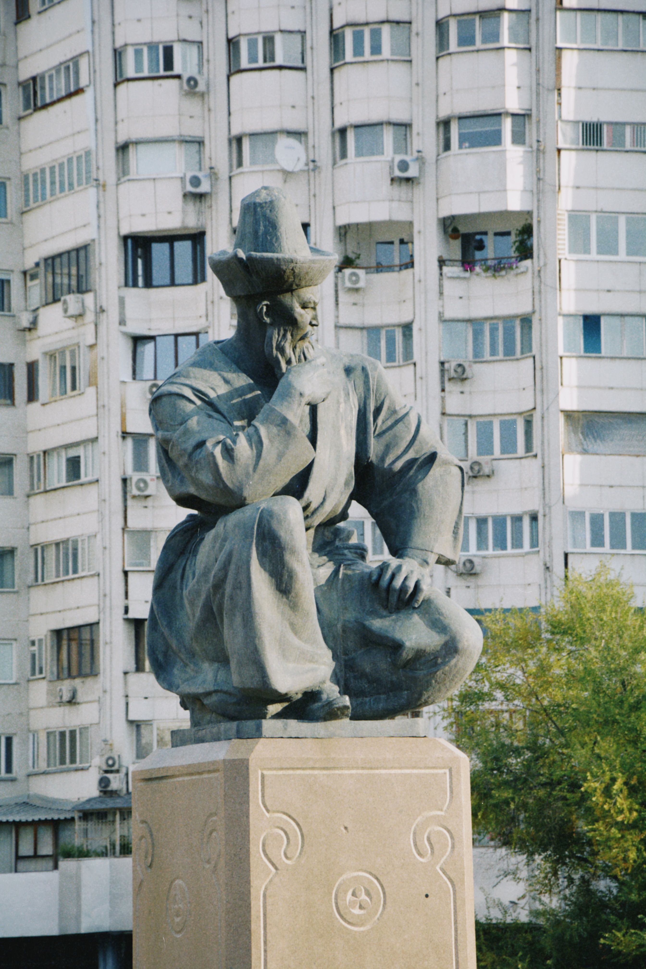 A striking statue in Almaty, Kazakhstan, against a backdrop of urban architecture.