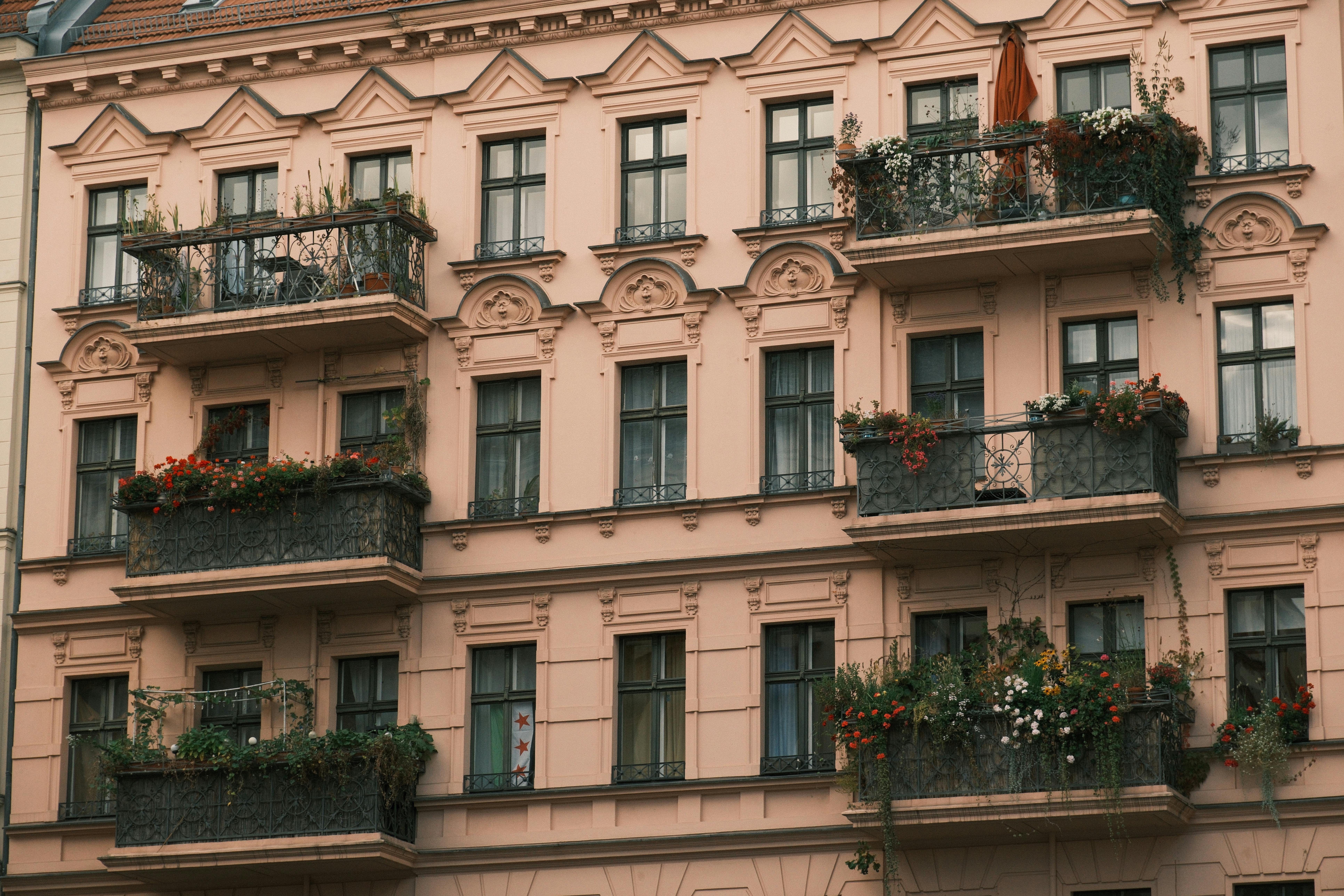 A detailed view of a European-style apartment building with ornate balconies decorated with plants.