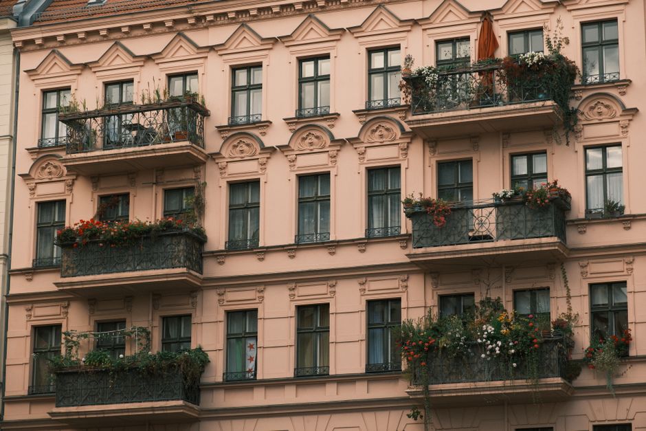 A detailed view of a European-style apartment building with ornate balconies decorated with plants.