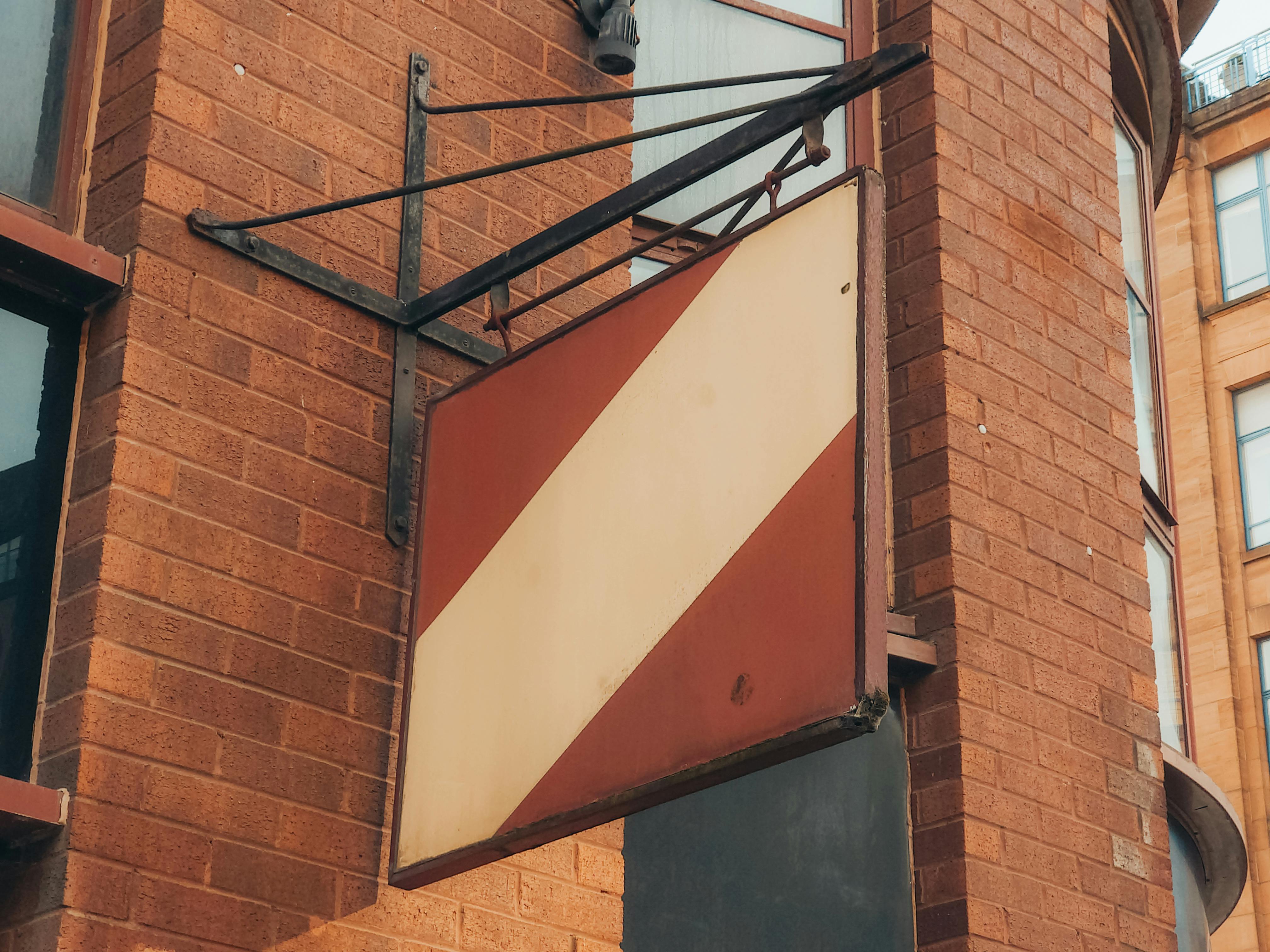 brick building with diagonal sign in urban setting