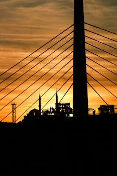 Beautiful silhouette of a bridge and city skyline against a golden sunset sky.