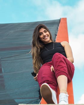 一位穿着红裤子、黑上衣的快乐女人坐在外面，享受着这一天