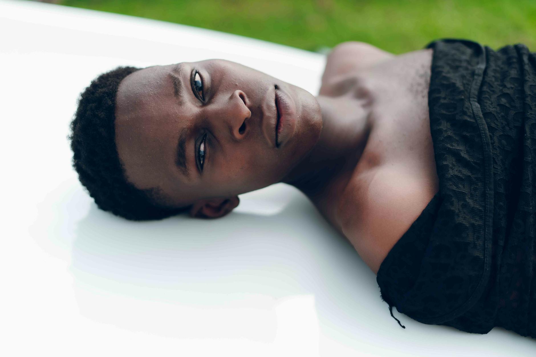 Close-up portrait of a young man lying down outdoors in Nigeria.