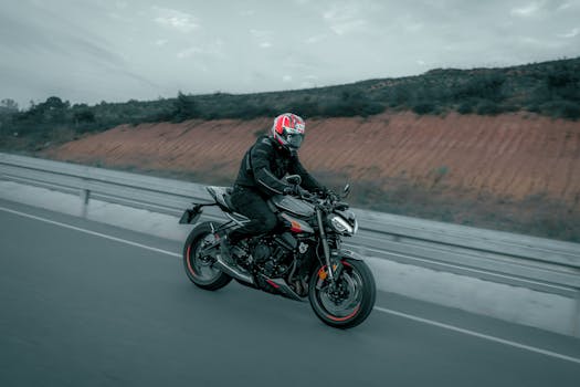 A biker on a black motorcycle cruising along an open highway, showcasing speed and freedom.