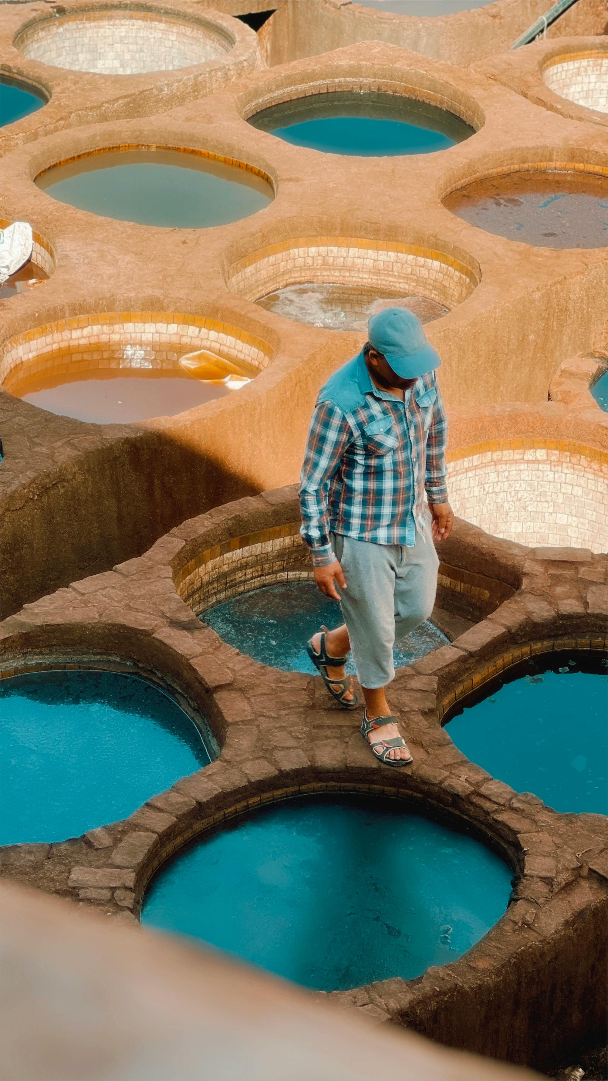 Man walking in vibrant Moroccan tannery vats, capturing cultural heritage and colorful dye production.