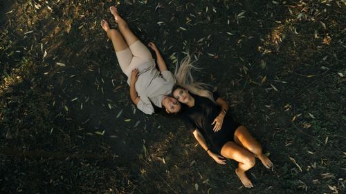 Free Two women in casual outfits lying on forest ground, enjoying nature. Stock Photo