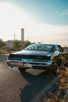 Classic black car on a sunny road, perfect for travel and vintage enthusiasts.