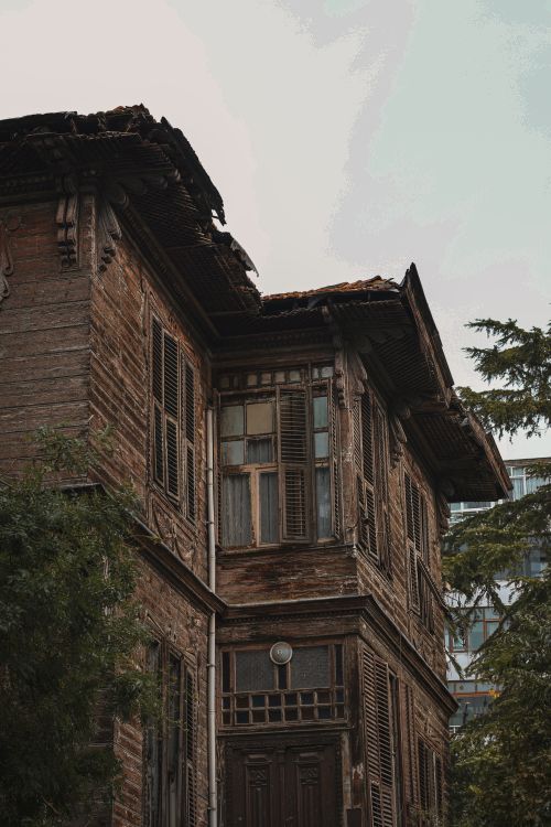Free A close-up view of a weathered wooden house showing architectural details and decay. Stock Photo